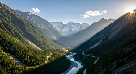 Sunburst over a winding river valley with dense pine forests and snow capped mountains