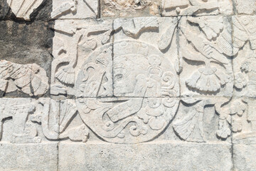 an ancient mayan carves stone with a skull into a ball at ball game field structure into Chichen Itza archaeological site