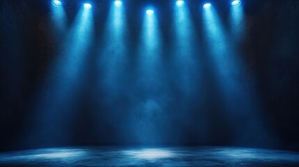 Empty dark stage illuminated by blue spotlights with visible beams of light and subtle fog creating a dramatic and mysterious atmosphere