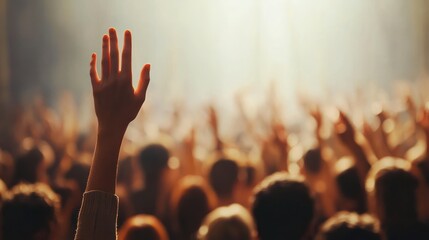 Raised hand in a crowd with warm, soft lighting capturing a moment of participation, unity, and anticipation among many blurred people