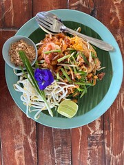 Pad Thai with seafood in a green plate on the table