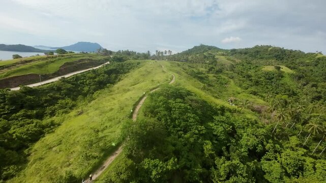 Energetic FPV flight skimming the Bato ni Ningning ridge trail above palm-covered hills, revealing Long Beach and the turquoise coast of San Vicente under soft daylight.