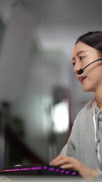 An IT helpdesk technician provides remote support, logging ticket details into a CRM system. She is troubleshooting a user's technical issue in a busy 24 and 7 support center.