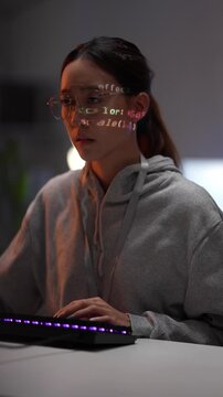 A young woman in a hoodie works on her computer in a dark room. Lines of code from the screen are projected onto her face, showing her deep focus on future technology.
(158 characters)