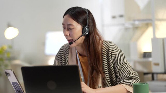 An IT helpdesk technician provides remote support, logging ticket details into a CRM system. She is troubleshooting a user's technical issue in a busy 24 and 7 support center.