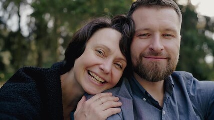 A close-up image of a joyful couple embracing in a lush park, displaying happiness and affection with genuine smiles. Happy Couple Embracing in a Sunny Park Setting, Love and Joy