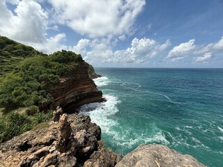 Coastal Beauty: A breathtaking vista of a rugged coastline, where emerald waves crash against ancient cliffs under a sky painted with puffy clouds.