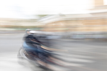 Blurred motion image of a motorcyclist riding fast on city street with SELECTIVE FOCUS, creating abstract light trails