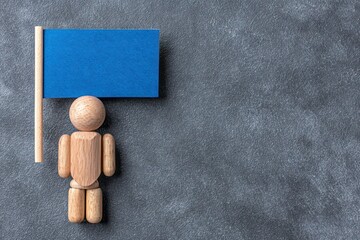 Wooden figure holds blue flag on textured surface
