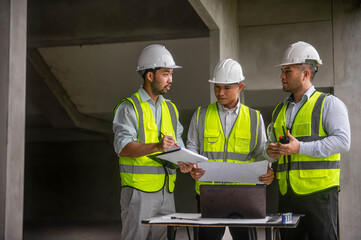 Expert architects are seriously brainstorming on the blueprints of an office building.