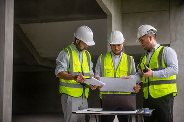 Expert architects are seriously brainstorming on the blueprints of an office building.