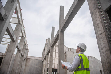 A specialist inspector is checking the building structure from the blueprints to ensure it meets the standards.