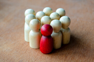 A red figurine tightly enclosed by beige figurines symbolizing pressure that can suggest leadership or harassment.