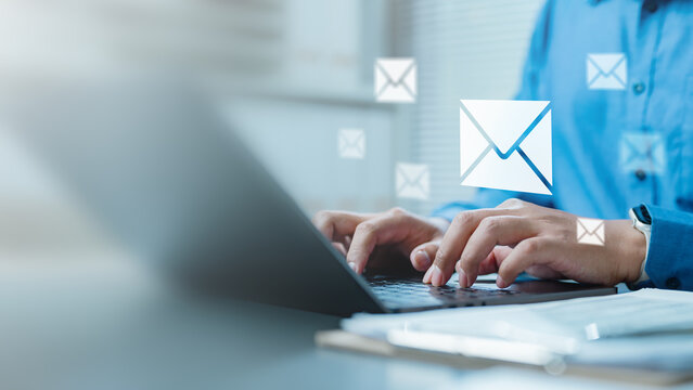 Businessman typing on laptop with floating email icons, concept of email communication, online messaging, digital marketing, newsletter, email automation, and corporate contact.