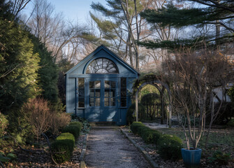 Charming old blue garden shed surrounded by lush greenery and flowers