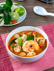 Prawn Tom Yum in a white bowl on a wooden table