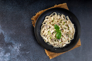 Pasta carbonara cream sauce with mushroom in a black plate