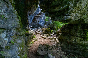 The entrance to Grieg's Caves in Ontario invites exploration amid the stunning natural rock formations and lush greenery.