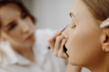 Make-up artist at work. Applying make-up to model face.