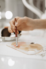 Makeup artist, makeup, brush paint concept. Makeup artist dips brush into paint. Close-up vertical