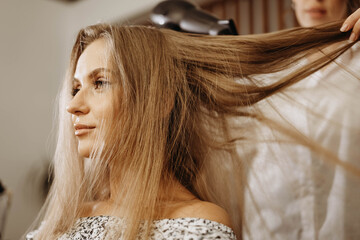 Makeup artist hairdresser blow drying model hair