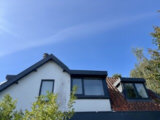 Charming house with tiled roof and black framed windows under blue sky