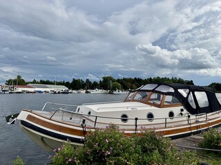 Naklejka premium Elegant yacht moored by green plants near calm water harbor