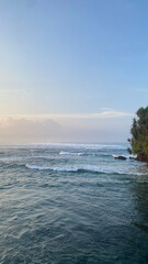 wide view of sea waves from the top of the hill bush with a slightly orange blue twilight sky