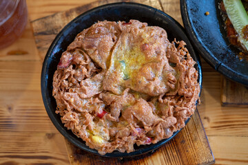 A freshly cooked, thick, and crispy Indonesian omelette (Telur Dadar), golden brown with crunchy edges, served in a rustic black stone bowl (cobek) on a wooden table. Authentic street food dish.