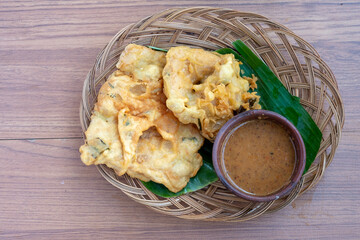 A top-down view of Tempe Mendoan, a popular Indonesian snack. These are crispy, batter-fried fritters made from tempeh (fermented soybean cake), served with a savory peanut dipping sauce.