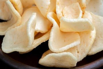 A close-up shot of a pile of white, crunchy prawn crackers, with a rough texture.