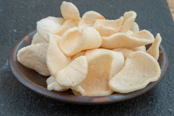 A close-up shot of a pile of white, crunchy prawn crackers, with a rough texture.