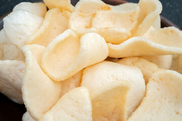 A close-up shot of a pile of white, crunchy prawn crackers, with a rough texture.