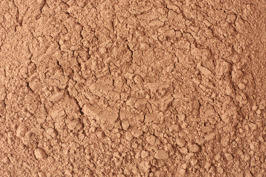 reddish-brown rock phosphate powder with cracked surface and granular texture, essential nutrient for plants, used as agricultural fertilizer, close-up taken from above