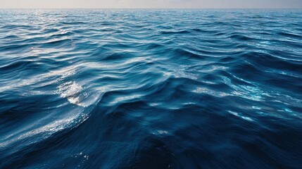 Fototapeta premium Ocean's Whispers: The boundless ocean stretches towards the horizon, a symphony of rolling waves in shades of blue. The gentle sea reflects the vastness of nature, stirring a sense of serenity.