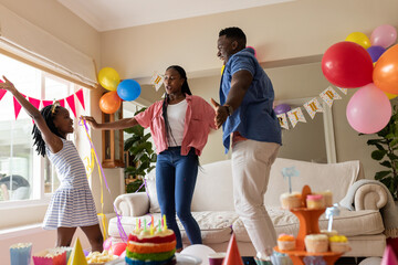 African American family celebrating birthday at home with balloons and cake