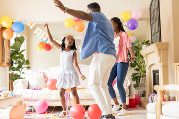Dancing joyfully, African American family celebrating colorful birthday at home