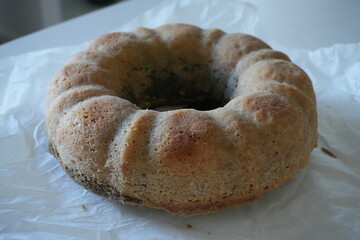 Homemade bundt cake without glaze on parchment paper, rustic autumn dessert with poppy seeds, traditional seasonal baking for cozy home and holiday table.
