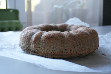 Homemade bundt cake without glaze on parchment paper, rustic autumn dessert with poppy seeds, traditional seasonal baking for cozy home and holiday table.
