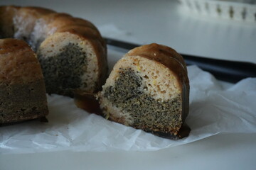 Slice of homemade bundt cake with poppy seeds and caramel glaze, rustic autumn dessert on parchment paper, cozy seasonal baking symbolizing warmth and tradition.