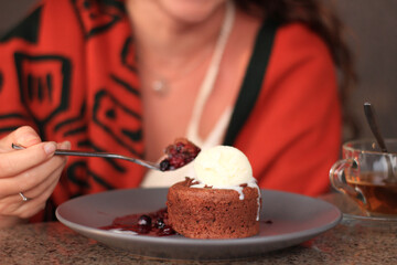 Image of vanilla ice cream with berry sauce on a gray plate, with tea nearby.