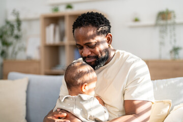 Fototapeta premium Happy african american father playing with baby at home, family love concept, parenting moments full of joy and care, father day and childhood connection, baby wellness and child insurance support