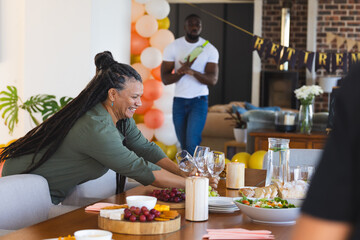 Woman arranging table for retirement party with food and decorations at home