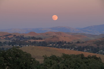 The July Full moon rises above the golden hills of the East Bay in Northern California