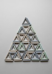 Arrangement of pastel cylinders forming a geometric triangular pattern