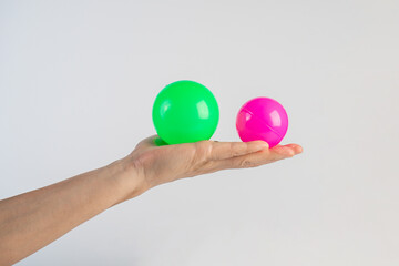 Pink and green plastic ball in hand, white background