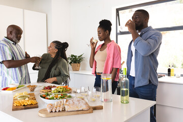 Family enjoying drinks and conversation in modern kitchen during celebration