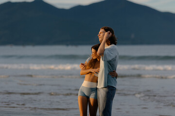 Young couple embracing on beach with mountain view at sunset