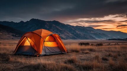 Tent glows at dusk in grand teton national park with mountains in background, wyoming, usa