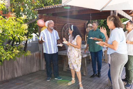 Seniors enjoying outdoor birthday party, sharing laughter and cake on wooden deck